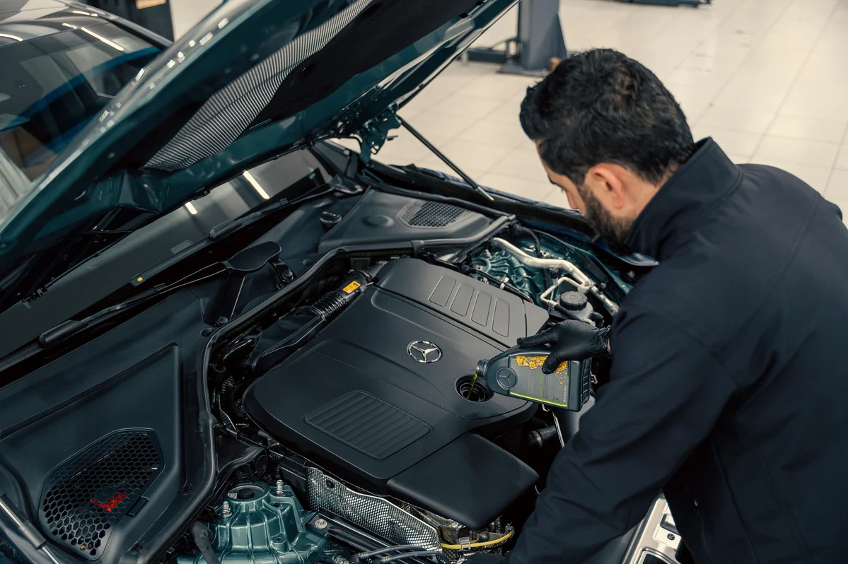 Mechanic inspecting a car engine for ticking sounds Mechanic inspecting a car engine for ticking sounds