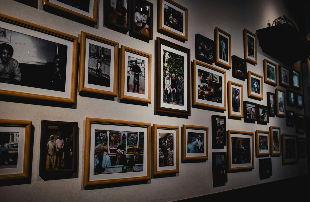 A diverse collection of art pieces including photos, prints, and textiles on a wall A diverse collection of art pieces including photos, prints, and textiles on a wall