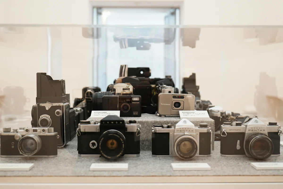 Collection of various vintage cameras displayed on a shelf Collection of various vintage cameras displayed on a shelf
