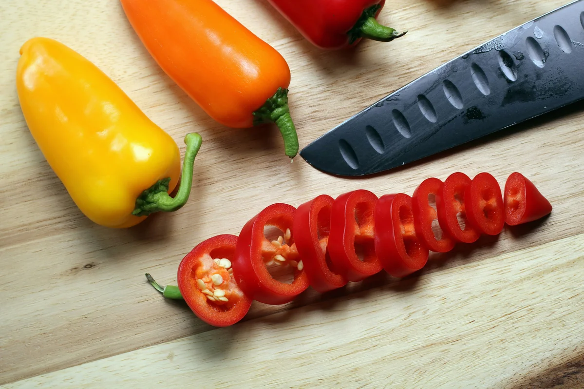 Chili pepper slices on a wooden cutting board with knife Chili pepper slices on a wooden cutting board with knife