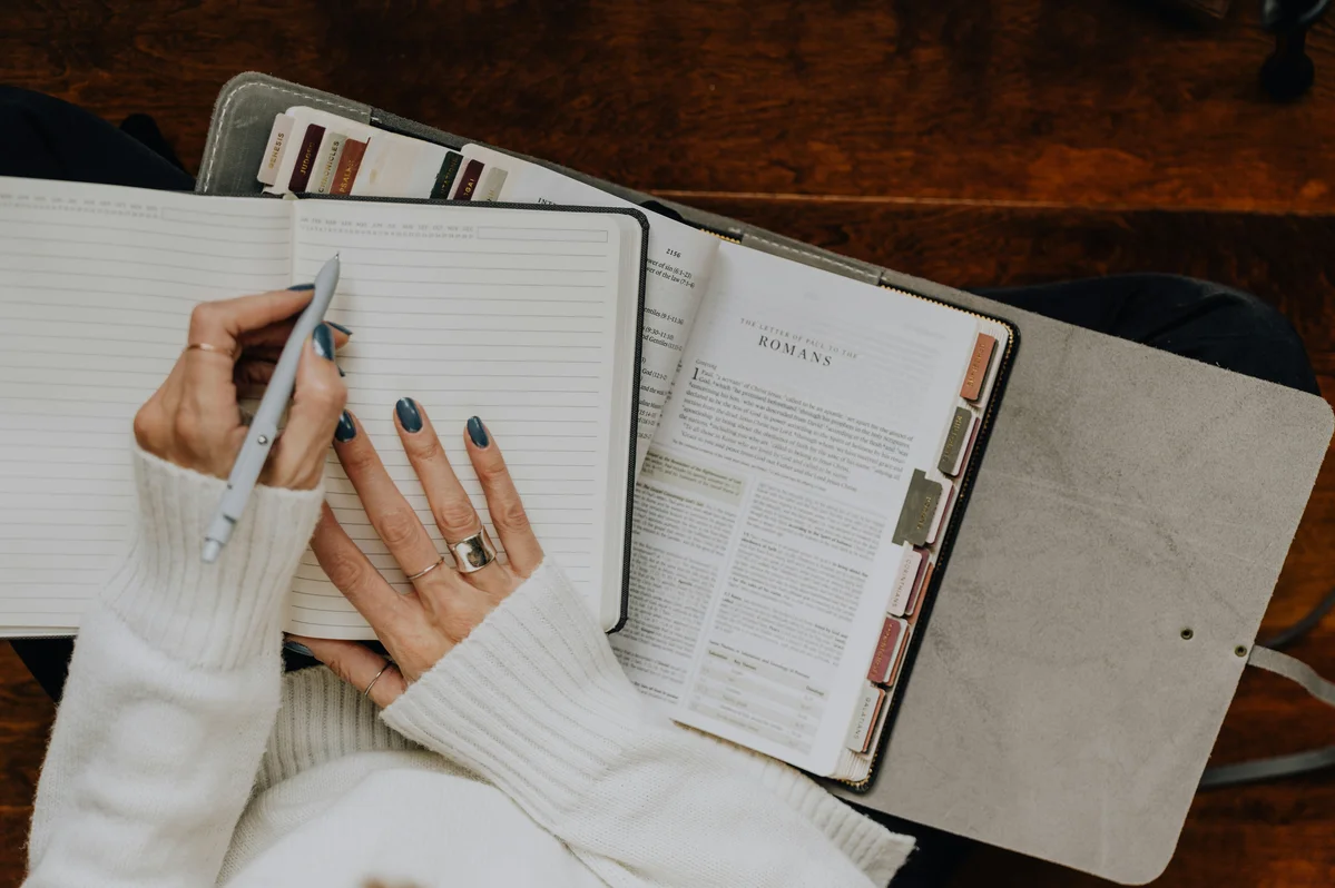 Person planning their day with a notebook and pen Person planning their day with a notebook and pen
